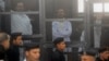 FILE - Political activists Ahmed Maher (R), Ahmed Douma (C) and Mohamed Adel, founder of 6 April movement, look on from behind bars in Abdeen court in Cairo, December 2013.
