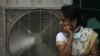 FILE - An Indian women stands in front of an air cooler to cool herself on a hot summer day in Hyderabad, in the southern Indian state of Telangana. The equatorial Pacific Ocean’s climate cycle “El Niño” effect, a warming of sea surface temperatures that occurs every few years, is getting much of the blame for the heat wave and drought. 