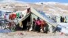 FILE - Syrian refugees sit by their tent in a Syrian refugee camp on the Lebanese border town of Arsal, in the eastern Bekaa on December 15, 2013. 