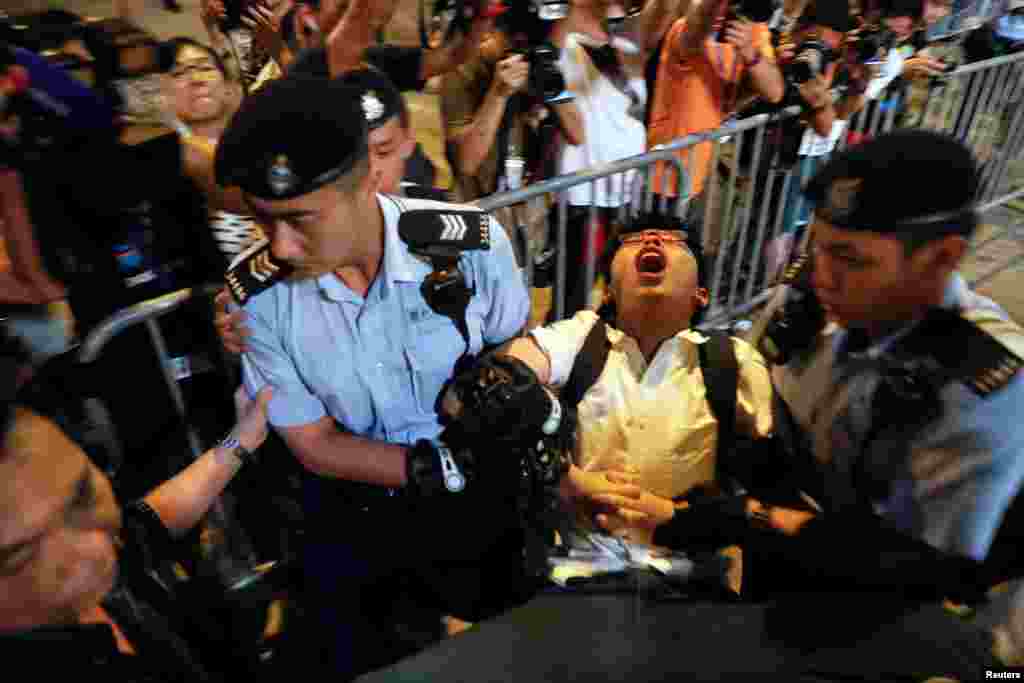 មេដឹកនាំបាតុកម្មនិស្សិត Joshua Wong ស្រែកនៅពេលដែលលោកត្រូវបានចាប់ខ្លួនរួមទាំងក្រុមបាតុករនៅវិមានដែលតំណាងទីក្រុងដែលបានប្រគល់ការកាន់កាប់ពីអង់គ្លេសមកចិន មួយថ្ងៃមុនប្រធានាធិបតីចិន Xi Jinping មកដល់ដើម្បីអបអរនៅទីក្រុងហុងកុង។