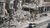 Men ride on a pick-up truck past damaged buildings in the rebel-held Bab al-Hadid neighbourhood of Aleppo, Syria Aug. 18, 2016. 