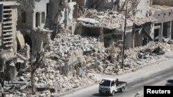 Men ride on a pick-up truck past damaged buildings in the rebel-held Bab al-Hadid neighbourhood of Aleppo, Syria Aug. 18, 2016. 