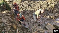 Sejumlah warga bekerja membersihkan lumpur di lokasi tanah longsor di desa Yambali di provinsi Enga, Papua Nugini, pada 27 Mei 2024. (Foto: AFP/Emmanuel Eralia)