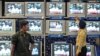 Indian salesman tunes televisions at an electronics shop as government official on screen pledges to boost spending for rural infrastructure, 2006 (file photo).
