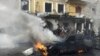 People gather near a burning car at the site of an explosion in the Shi'ite town of Hermel January 16, 2014. A car bomb exploded near a local government building.