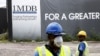 FILE - Construction workers stand in front of a 1Malaysia Development Berhad (1MDB) billboard at the Tun Razak Exchange development in Kuala Lumpur, Malaysia.