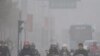 Chinese motorists ride their electric bikes in heavy fog down a street in Hefei, east China's Anhui province, 25 Nov 2009