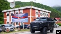 Mobil polisi khusus Republik Spska melintas di depan papan iklan yang bertuliskan "Kami bukan negara genosida" di Srebrenica, Bosnia, 23 Mei 2024. PBB akan voting draf resolusi untuk menetapkan 11 Juli sebagai Hari Internasional Genosida di Srebenica. (Foto: /Armin Durgut/AP)