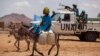 FILE - A man rides his donkey past Tanzanian UNAMID troops standing guard at a camp for internally displaced people (IDP) in Khor Abeche, South Darfur, Sudan. 
