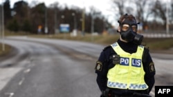 A police officer wearing a gas mask stands guard at the scene after emergency services were alerted to Sweden's Security Service headquarters in Solna, north of Stockholm, because of a suspected gas leak on Feb. 23, 2024.