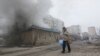 A woman resident passes by a burning house in Mariupol, Ukraine, Jan. 24, 2015.