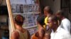 FILE - People read news headlines at a newsstand in Conakry, March 28, 2014. 