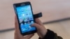 FILE - A woman uses an Android smartphone in Brussels, April 20, 2016. 
