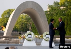U.S. President Barack Obama (R) puts his arm around Japanese Prime Minister Shinzo Abe after they laid wreaths in front of a cenotaph at Hiroshima Peace Memorial Park in Hiroshima, Japan. May 27, 2016.