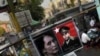 In this photo taken on Feb 23, 2012, people walk past a roadside stall selling the posters of Burmese democracy icon Aung San Suu Kyi and her late father in Rangoon, Burma. 