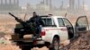 FILE - An anti-government rebel sits with an anti-aircraft weapon in front an oil refinery in Ras Lanouf, eastern Libya, March 5, 2011. The United States, France, Germany, Italy, Spain and Britain have called upon forces loyal to a Libyan general to withdraw from three eastern oil terminals seized earlier this week, in a statement, Sept. 13, 2016.