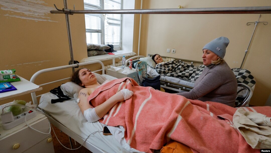 Una conocida visita un hospital y se sienta junto a Marina Klimenko, de 28 años, y Lyudmila Antonenko, de 46, trabajadoras heridas en un mercado que recientemente fue atacado por bombardeos en Donetsk, Ucrania, controlada por Rusia, 22 de enero de 2024. 