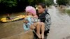A member to the Texas Army National Guard carries Daniel Lopez to dry ground as people evacuate a neighborhood that was inundated after water was released from nearby Addicks Reservoir, Aug. 29, 2017, in Houston, Texas.