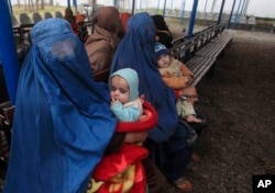 FILE - Afghan refugee women sit with their babies as they wait with others to be repatriated to Afghanistan, at the United Nations High Commissioner for Refugees (UNHCR) office on the outskirts of Peshawar, Feb. 2, 2015.