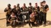 Kurdish Peshmerga fighters pose with an Islamic State flag, which they pulled down after capturing Mount Batnaya, near Zummar, Sept. 20, 2014.