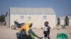FILE - In this photo taken on Dec. 10, 2019 a displaced Burkinabe woman and child prepare food, in the Pissila town camp, near Kaya, Burkina Faso. 