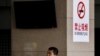 FILE - A Chinese man smokes in front of a pillar with a no smoking notice on display at a bus station in Beijing, March 24, 2011