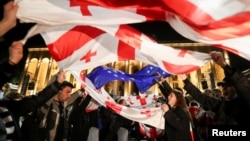 Demonstran mengibarkan bendera saat unjuk rasa memprotes RUU tentang "agen asing" di Tbilisi, Georgia, 13 Mei 2024. (Foto: REUTERS/Irakli Gedenidze)