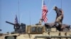 FILE - This April 29, 2017, still taken from video, shows an American soldier standing on an armored vehicle in the northern village of Darbasiyah, Syria. 