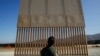 FILE - A U.S. Border Patrol agent looks at one of border wall prototypes in San Diego, June 28, 2018. 