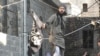 A handout image released by the Syrian opposition's Shaam News Network allegedly shows a Syrian opposition activist waving an black flag of the Islamist Jihadists who are accused of recruiting children. 