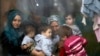 Syrian refugees look through a window inside a refugee centre as they wait for a distribution of humanitarian aid by volunteers of the Bulgarian Red Cross in Sofia.