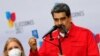 Le président vénézuélien Nicolas Maduro tenant un exemplaire miniature de la constitution lors d'une allocution en présence de son épouse Cilia Flores, après avoir voté aux élections régionales, à Caracas, le 21 novembre 2021.