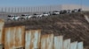 FILE - U.S. Border Patrol vehicles are parked along a secondary fence as they respond to a group of Central American migrants crossing the border wall illegally, seen from across the wall in Tijuana, Mexico, Dec. 9, 2018.