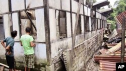 Indian people inspect a house damaged by vandals in Kokrajhar, India, July 23, 2012.
