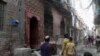FILE - Residents look at the house of a family belonging to the Ahmadi sect, which was torched by angry mob in Gujranwala, Pakistan, July 28, 2014.
