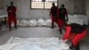 FILE - Workers wrap the bodies of dead fighters loyal to Syrian President Bashar al-Assad at a morgue in Aleppo, Oct. 30, 2014. The opposition Free Syrian Army said it killed the men near Aleppo city and that some of the dead had Iranian and Afghan nationalities. 