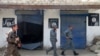 FILE - Afghan police walk past Islamic State militant flags on a wall, after an operation in the Kot district of Jalalabad province east of Kabul, Afghanistan, Aug. 1, 2016. Local officials and foreign military commanders in Afghanistan have played down concerns Islamic State is expanding activities beyond its traditional strongholds in the east.