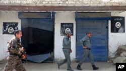 Afghan police walk past Islamic State militant flags on a wall, after an operation in the Kot district of Nangarhar province, Aug. 1, 2016.