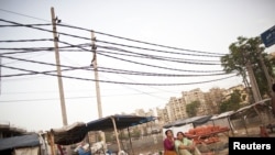 Potters rest on the roadside, under the overhead power cables at Gurgaon, on the outskirts of New Delhi June 17, 2012.
