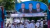Supporters of Prime Minister Hun Sen's Cambodian People's Party dance under portraits of the party leaders, from left, Chea Sim, Hun Sen and Heng Samrin, during an election campaign in Phnom Penh, Cambodia, Thursday, June 27, 2013.