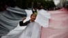FILE - A boy chants slogans through a gap in a national flag raised by Shi'ite rebels, known as Houthis, during a protest against Saudi-led airstrikes in Sanaa, Yemen, April 15, 2016. 