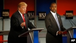 Donald Trump speaks as Ben Carson listens during the Republican presidential debate at the Milwaukee Theatre, Nov. 11, 2015, in Milwaukee