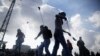 FILE - Palestinian protesters use slingshots to throw stones towards Israeli security forces during clashes following a protest marking the 11th anniversary of the death of late Palestinian leader Yasser Arafat, in the West Bank city of Ramallah, Wednesda