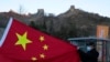 A visitor holds the Chinese flag near the Badaling section of the Great Wall of China on the outskirts of Beijing on Feb. 8, 2022.