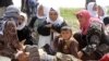 FILE - More than 200 Yazidi sect members, freed eight months after they were taken captive by Islamic State militants, wait on the edge of Kirkuk for relocation, April 8, 2015.