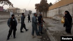 A woman talks to Afghan policemen to allow her to pass as they stand guard near the site of a suicide attack that wounded Afghanistan's spy chief in Kabul, Dec. 6, 2012.