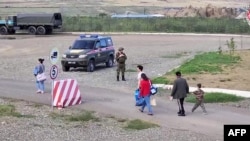 아제르바이잔 측 군사활동 지역에서 피란민들이 이동하는 가운데 러시아 평화유지군(가운데)이 서 있다. 20일 러시아 국방부 공개 영상 캡쳐.
