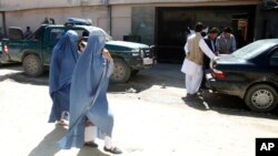 Afghan women walk past Park Palace guesthouse, May 14, 2015 after being attacked by gunmen in Kabul, Afghanistan. 