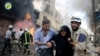 FILE - This photo taken June 8, 2016, and provided by the Syrian Civil Defense Directorate in Aleppo province, shows Syrian civil defense workers helping an injured woman after warplanes attacked a street, in Aleppo, Syria.