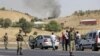 Turkish soldiers take security measures on a main road which connects eastern Turkish cities Bingol and Mus, as smoke rises from a burning vehicle attacked by PKK in the background, September 18, 2012. 